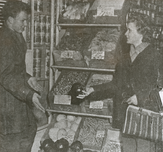 875337 Afbeelding van broer en zus Gerard jr. en Rie Broekman die als winkelier en klant poseren voor een folder ...